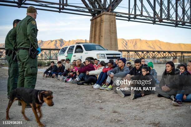 Group of about 30 Brazilian migrants, who had just crossed the border, sit on the ground near US Border Patrol agents, on the property of Jeff Allen,...