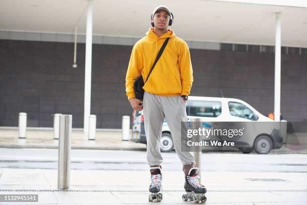 young man wearing roller skates on city street. - rolschaatsen schaats stockfoto's en -beelden