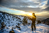 Hunter observing a beautiful vista while standing on a mountain ridge covered with snow
