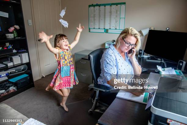 mother attempts to work from home on the computer and phone whilst also looking after her young daughter - berufstätige mutter stock-fotos und bilder