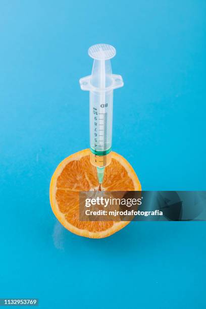 orange with a sringe stuck - cuestiones ambientales stock pictures, royalty-free photos & images