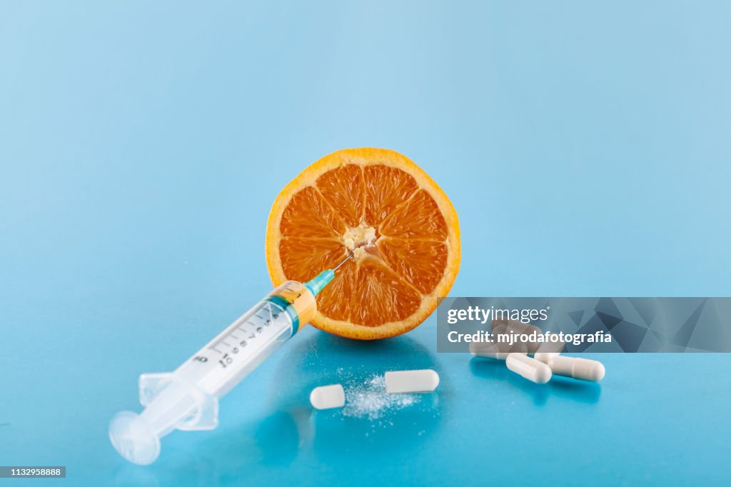 Orange with a sringe stuck and spills