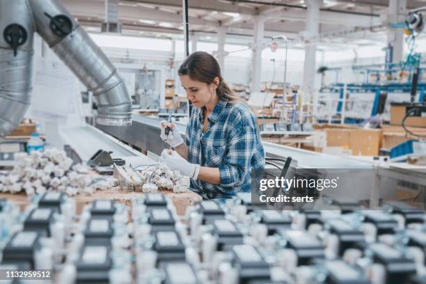 industriearbeiterin frau lötet kabel von fertigungsanlagen in einer fabrik - elektronik industrie stock-fotos und bilder