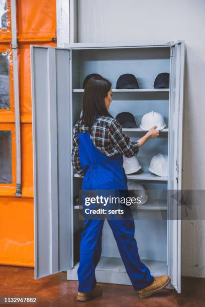 manuel worker woman taking industrial helmet on safety cabinet - mining hats stock pictures, royalty-free photos & images