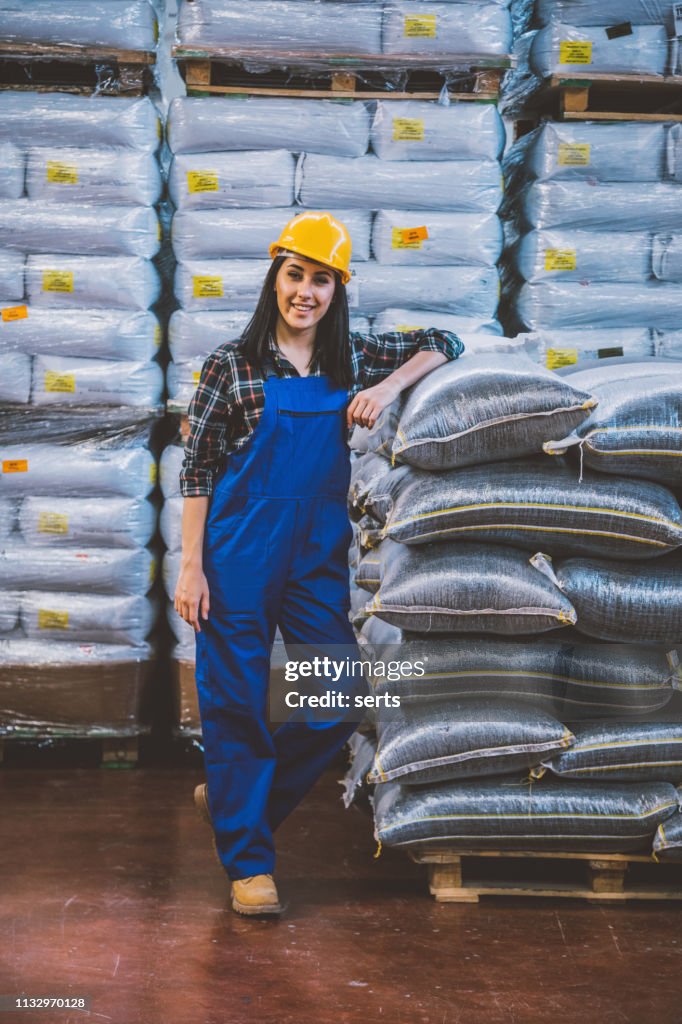 Portrait of young confident female worker in factory warehouse