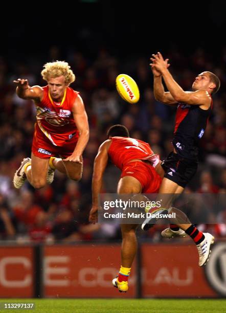 Josh Toy and Karmichael Hunt of the Suns contest a mark with David Zaharakis of the Bombers during the round six AFL match between the Essendon...