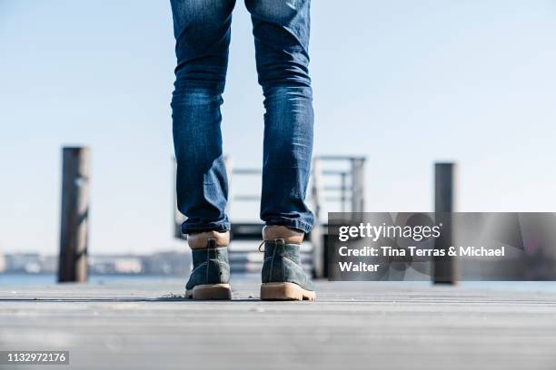 low section of man standing on pier on sunny day in germany. - schuhwerk fotografías e imágenes de stock