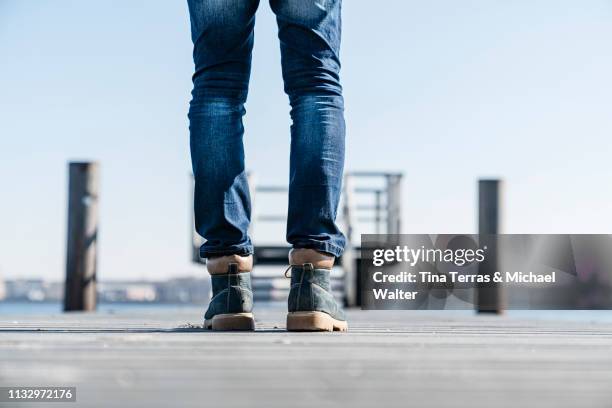 low section of man standing on pier on sunny day in germany. - körperbewusstsein stock pictures, royalty-free photos & images