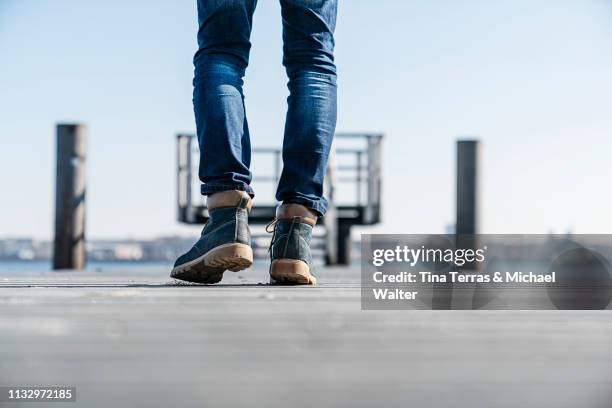 low section of man walking on pier on sunny day in germany. - körperbewusstsein stock pictures, royalty-free photos & images