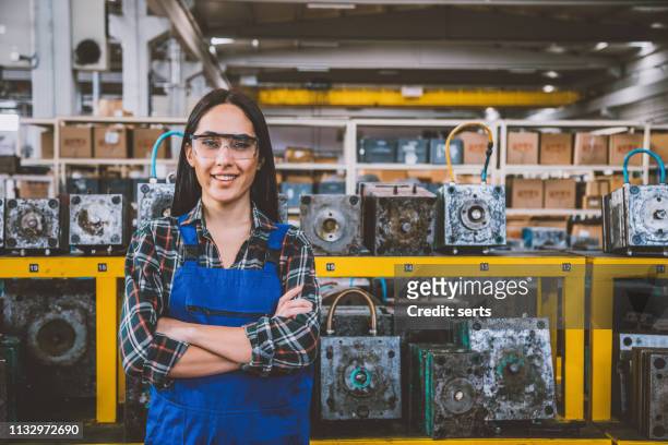 porträt der lächelnden jungen technikerin in fabrik - women in stem stock-fotos und bilder