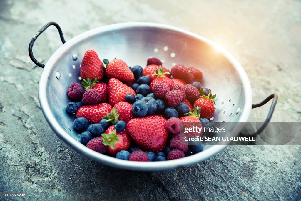 Strawberries, blueberries and raspberries in colander