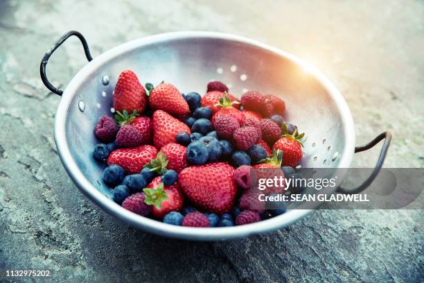 strawberries, blueberries and raspberries in colander - escorredor imagens e fotografias de stock