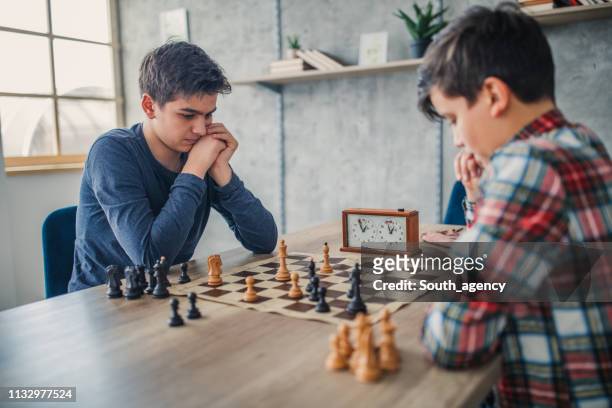 dos chicos inteligentes jugando al ajedrez en la escuela de ajedrez - finalmatch fotografías e imágenes de stock