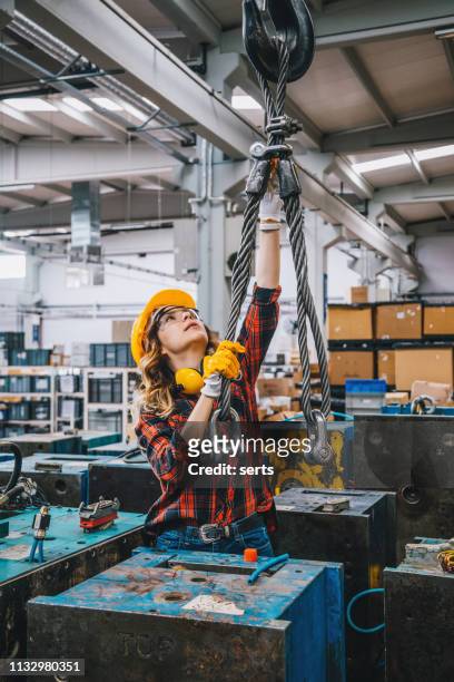 schwere industriearbeiterin arbeitet mit haken aus einem kran in fabrik - crane hook stock-fotos und bilder
