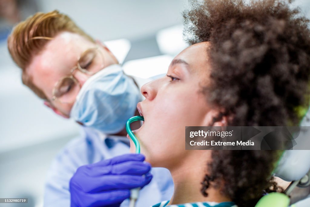 Putting a saliva ejector into the patient's mouth on a dental checkup