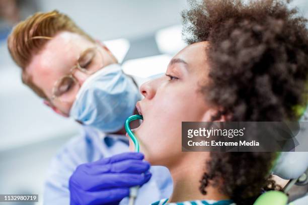 在牙科檢查中, 將唾液噴射器放入患者的口腔 - suction tube 個照片及圖片檔
