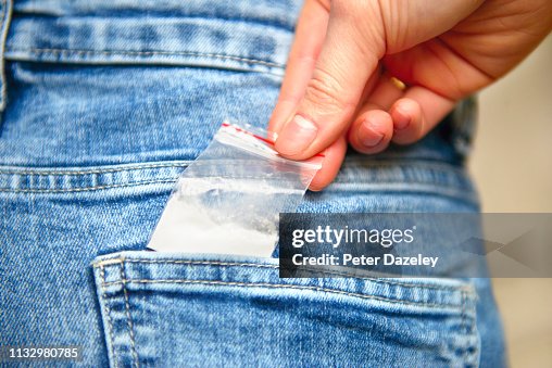 Teenage schoolgirl reaching for cocaine in her back jeans pocket Teenage schoolgirl reaching for cocaine in her back jeans pocket