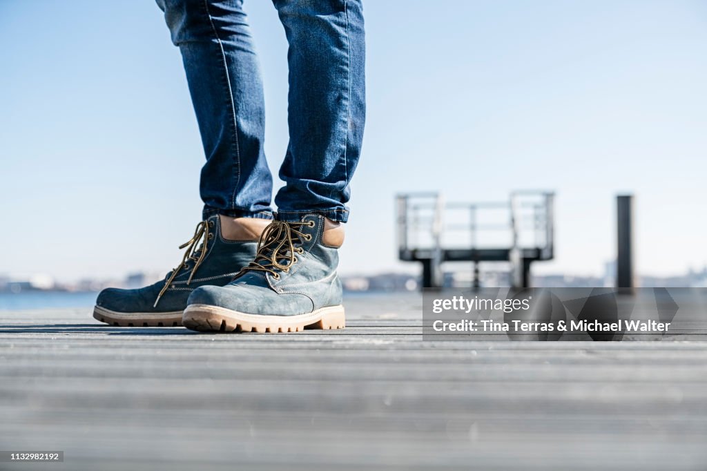 Low section of man standing on pier on sunny day in Germany.