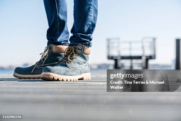 low section of man standing on pier on sunny day in germany. - riemenschuh stockfoto's en -beelden