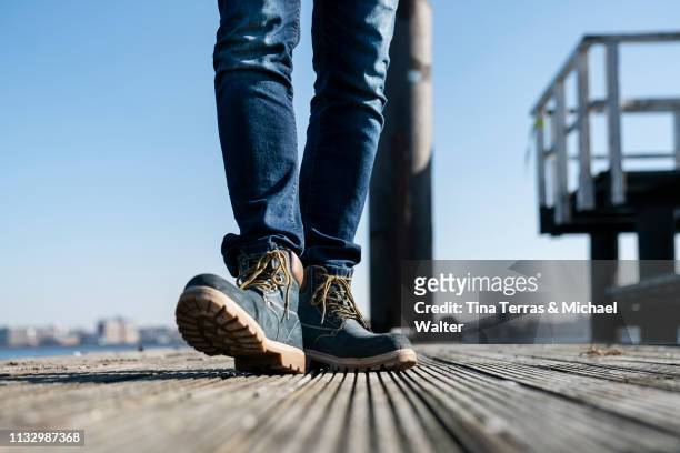 low section of man walking on pier on sunny day in germany. - schuhwerk fotografías e imágenes de stock