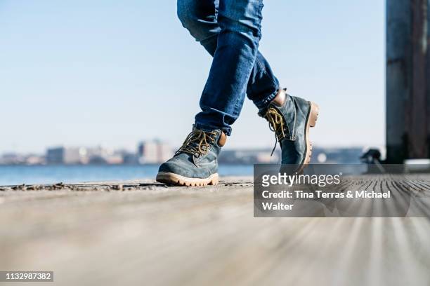 low section of man walking on pier on sunny day in germany. - schuhwerk fotografías e imágenes de stock
