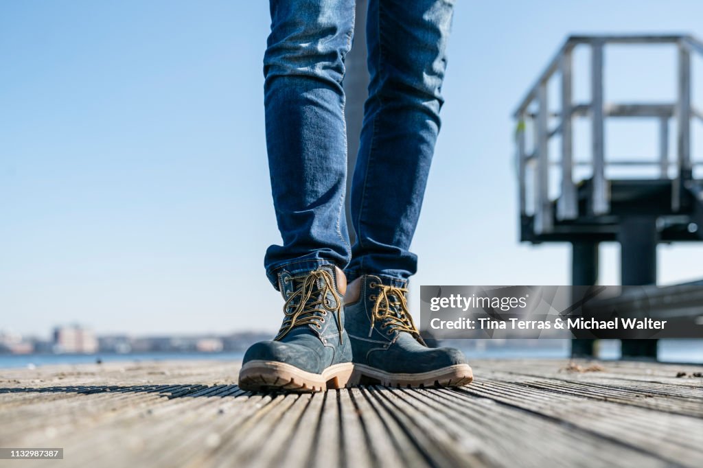 Low section of man walking on pier on sunny day in Germany.
