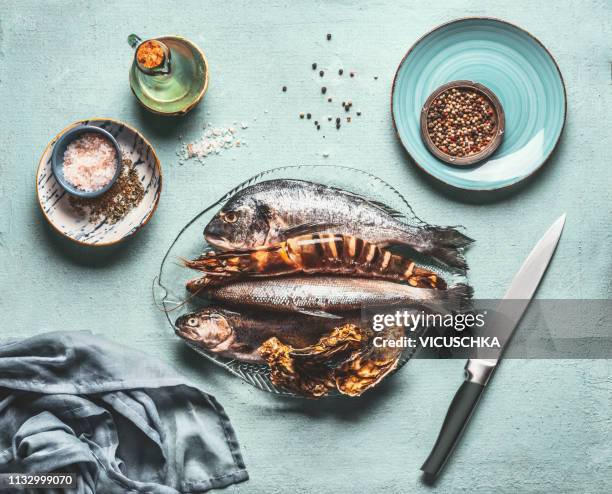 seafood cooking. fishes and crustaceans on kitchen table - dolphin fish fotografías e imágenes de stock