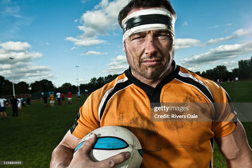 Rugby player holding ball on pitch, portrait