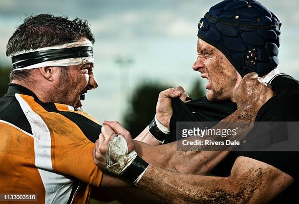 rugby players grappling with each other - se battre photos et images de collection