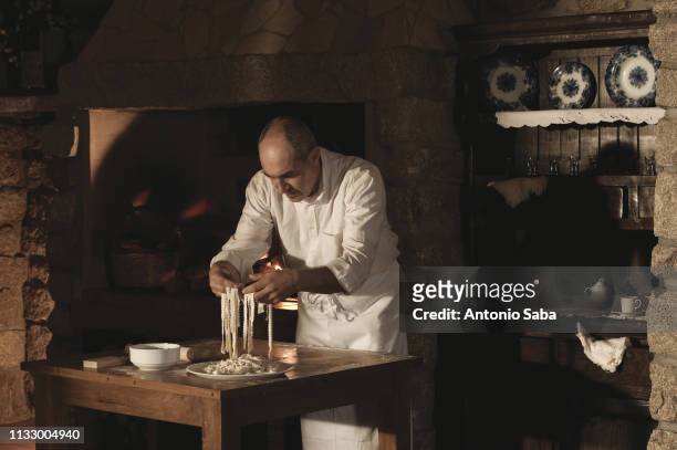 cook handling pasta dough in kitchen - italian culture - fotografias e filmes do acervo