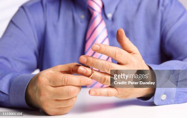 married man removing wedding ring prior to starting an affair - midlife crisis stock pictures, royalty-free photos & images