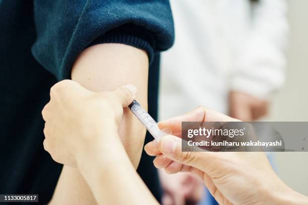 female doctor giving a vaccination shot to a young woman - vaccination ストックフォトと画像