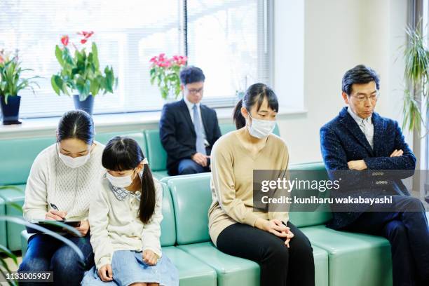 mother with young daughter filling out forms in a hospital waiting room - ミッドアダルト ストックフォトと画像