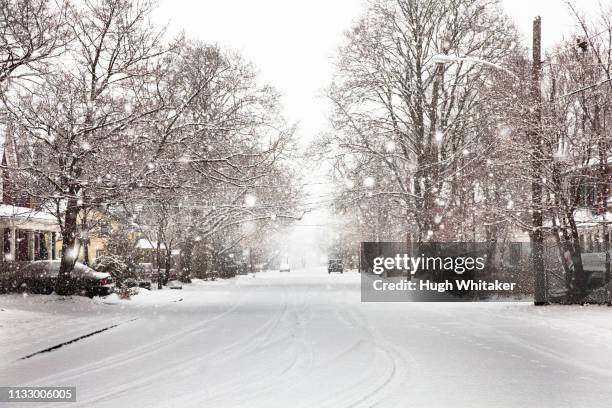 snow falling on suburban street - snow covered road stockfoto's en -beelden