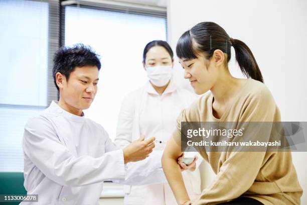 male doctor giving a vaccination shot to a young girl - injecting ストックフォトと画像