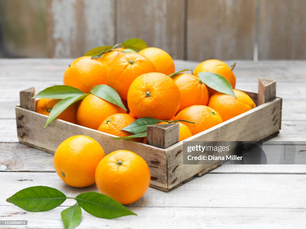 Oranges in vintage crate on whitewashed wooden table