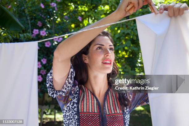 woman hanging sheets in the garden - ropa tendida fotografías e imágenes de stock
