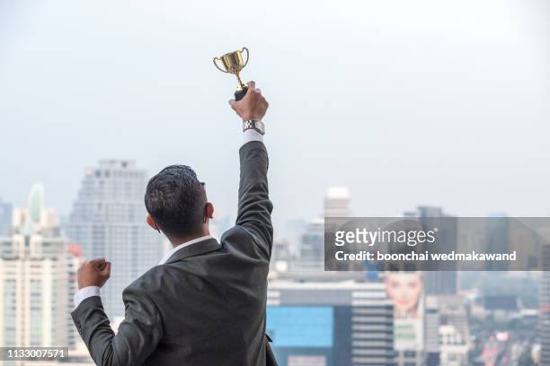 businessman celebrating with trophy - first light awards inside stock-fotos und bilder