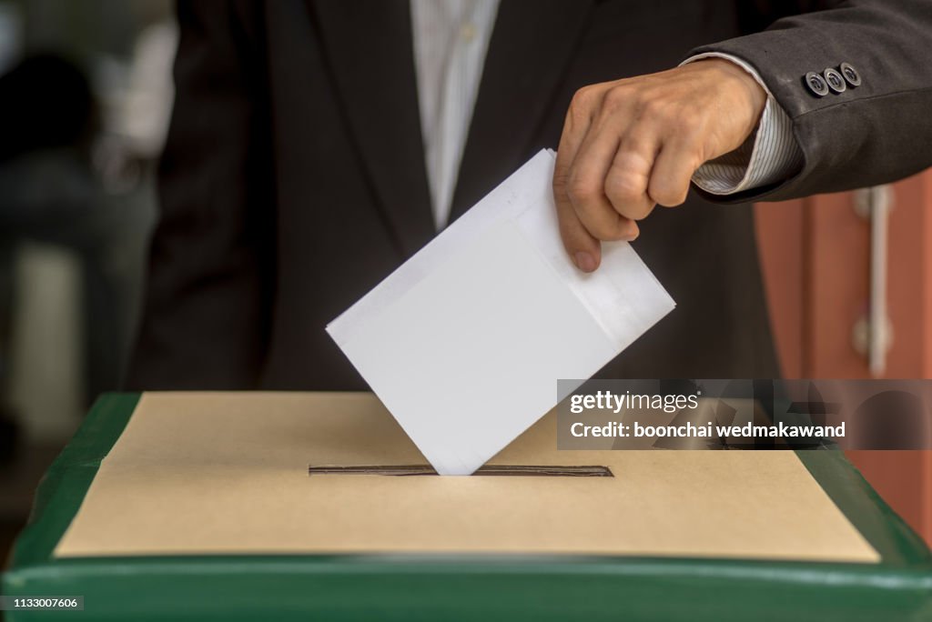 Hand of a person casting a vote into the ballot box during elections