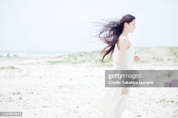 young woman with long windswept black hair on beach - 清らか ストックフォトと画像