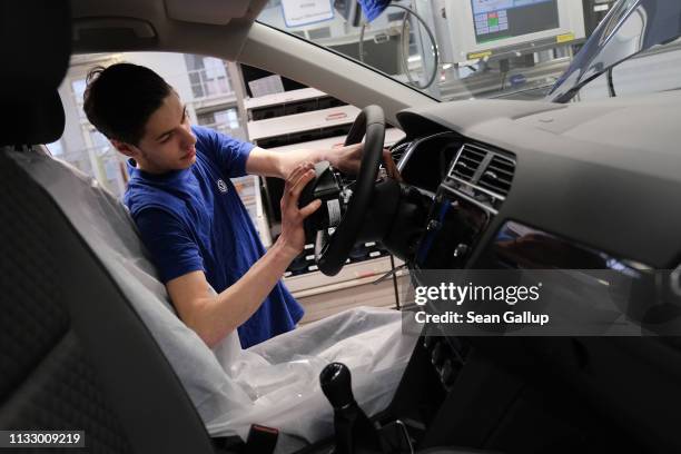 Workers installs an airbag into the steering wheel of a car on the assembly line for Volkswagen Touareg, Touran and T-Roc models at the Volkswagen...