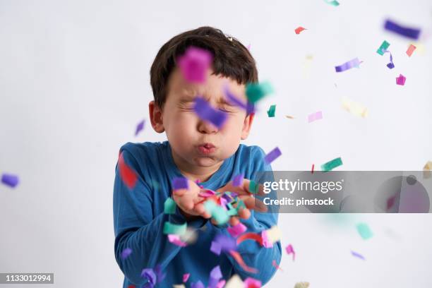 cute boy blowing the confetti at the camera - excitement confetti stock pictures, royalty-free photos & images