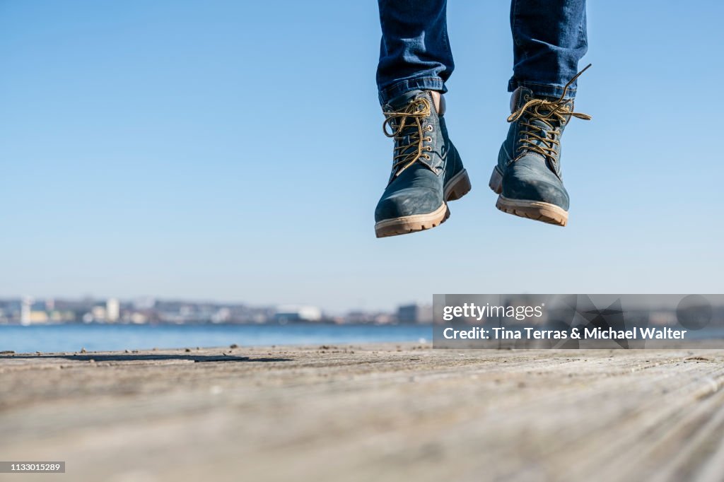 Low section of man jumping on pier on sunny day in Germany.