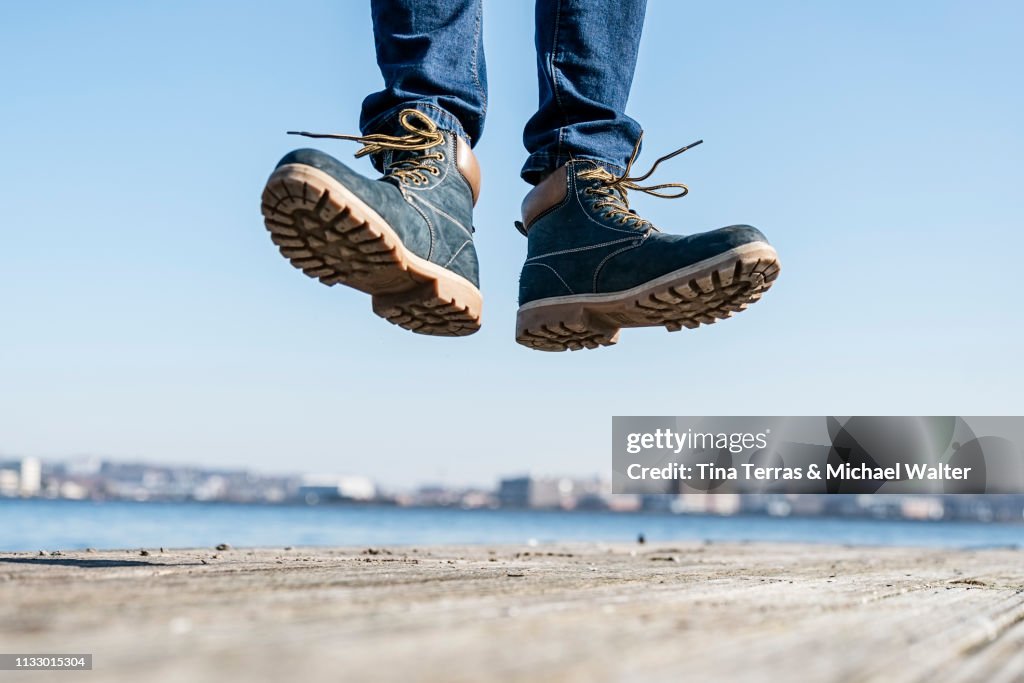 Low section of man jumping on pier on sunny day in Germany.