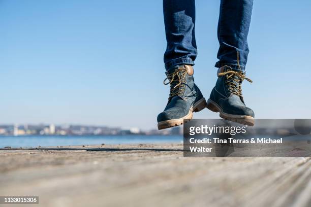low section of man jumping on pier on sunny day in germany. - körperbewusstsein stock pictures, royalty-free photos & images