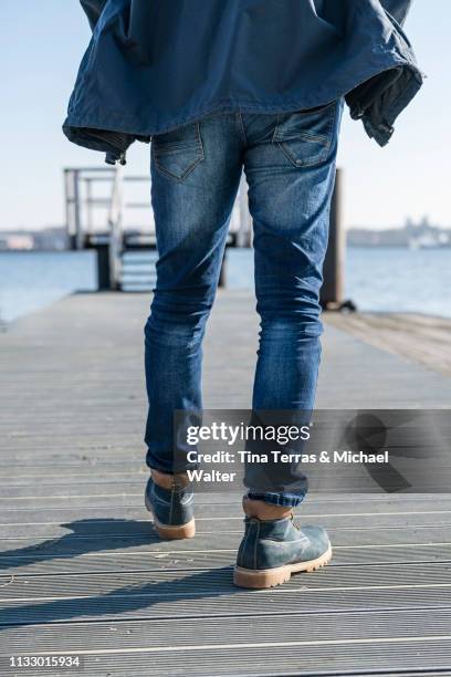 low section of man walking on pier on sunny day in germany. - schuhwerk fotografías e imágenes de stock