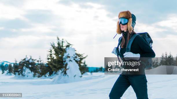 skieur de femme avec le sac à dos marchant par la forêt neigeuse - high fashion model photos et images de collection