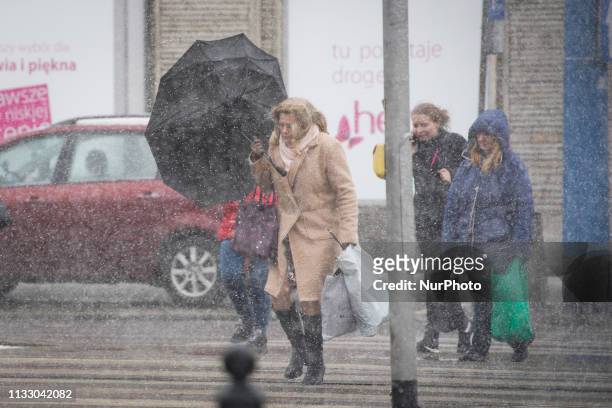 Woman holds on to her umbrella during a storm in Warsaw, Poland on March 26, 2019. A sudden hail storm, strong winds and a drop in temperature...