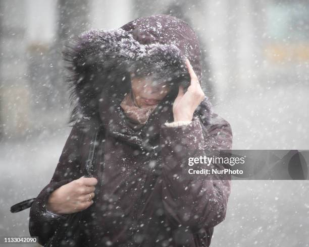 Woman holds on to her hoddie during a hail storm in Warsaw, Poland on March 26, 2019. A sudden hail storm, strong winds and a drop in temperature...