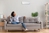 African young relaxed woman sitting on couch breathing fresh air